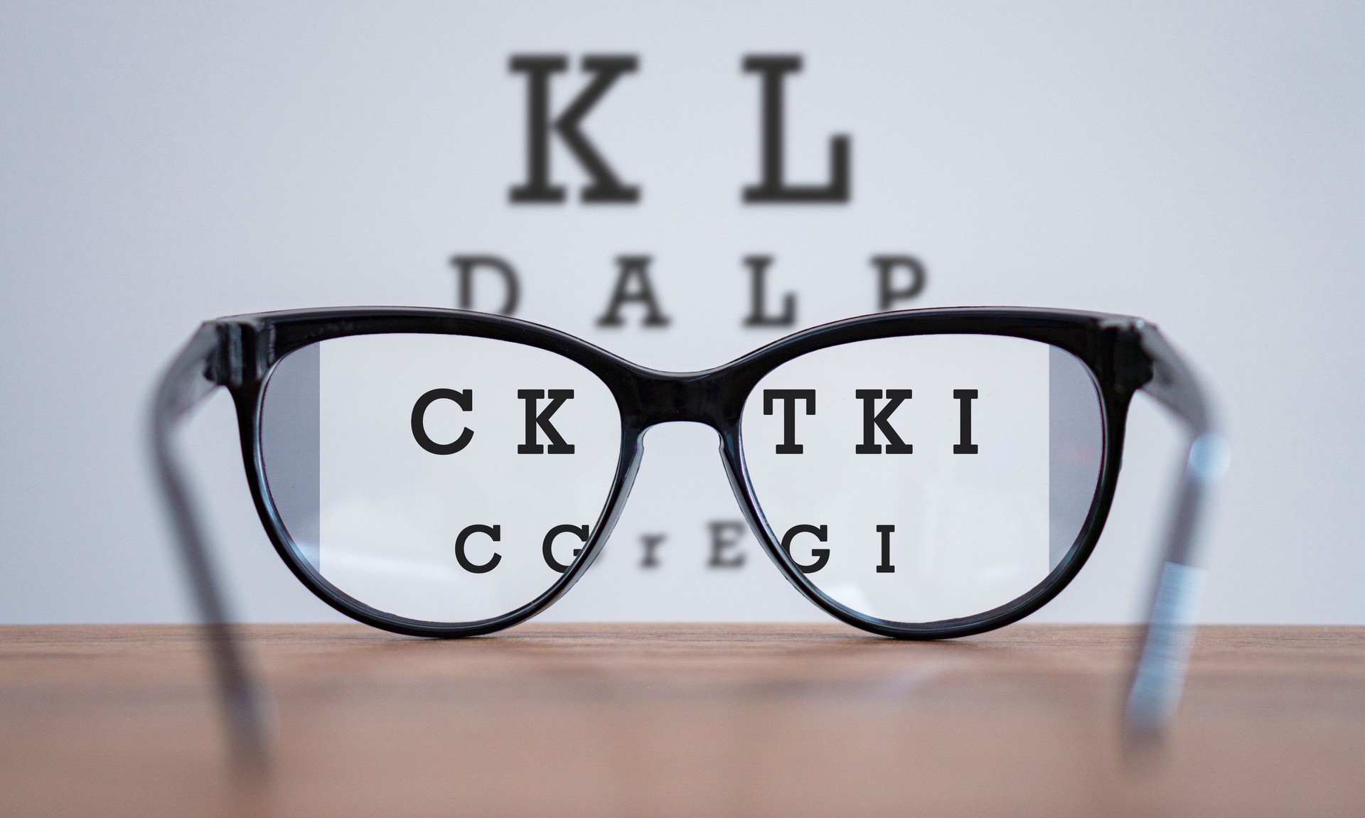 Eyeglasses during optometric examination concept with wooden table, Glasses on table and alphabet letter front view.